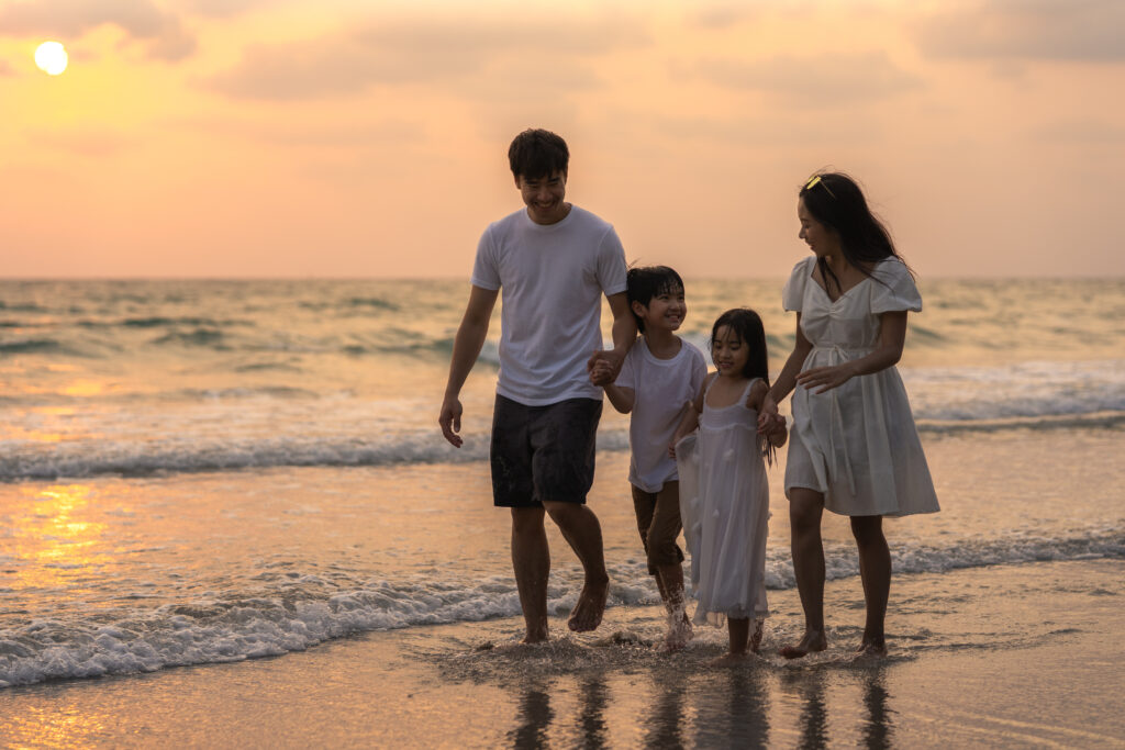 Asian young happy family enjoy vacation on beach in evening. Dad